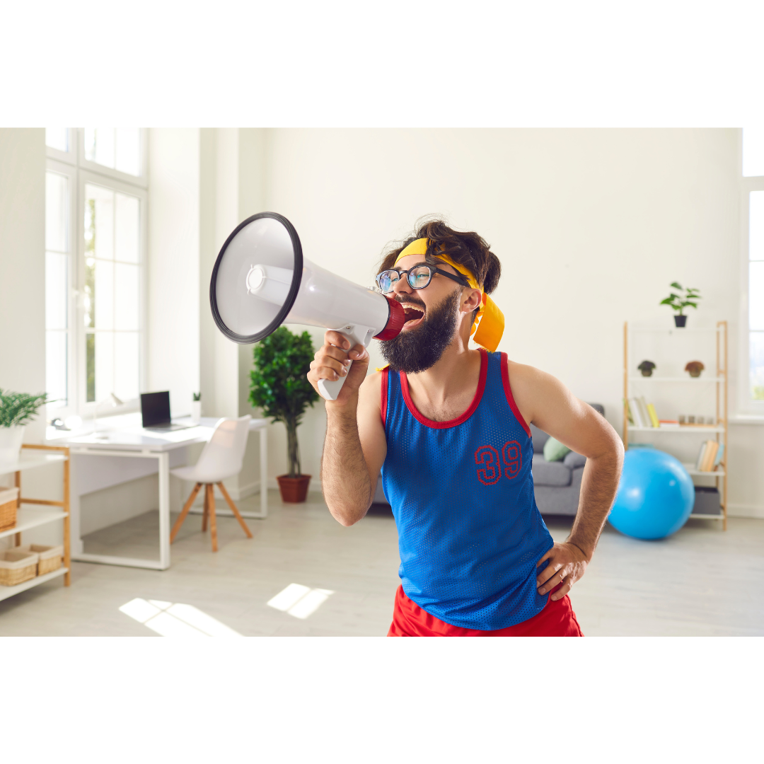 Bearded man in quirky sportswear shouting into a megaphone in a bright, playful office setting symbolising fun and energy in a dog friendly workplace.