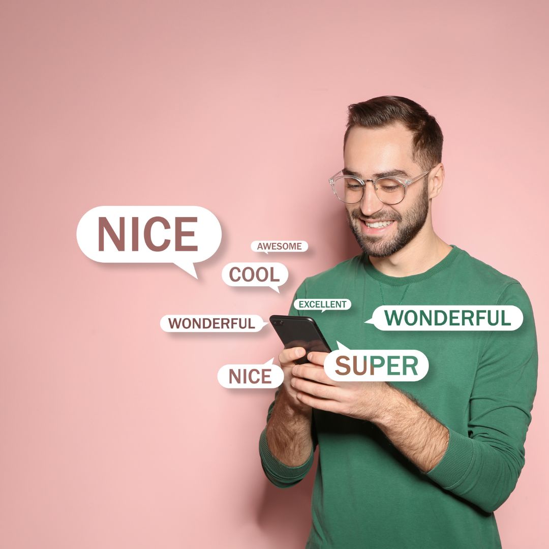 A smiling man wearing a green sweater and glasses looks at his smartphone, surrounded by floating speech bubbles containing positive words like "Nice," "Super," "Wonderful," and "Cool," against a soft pink background.