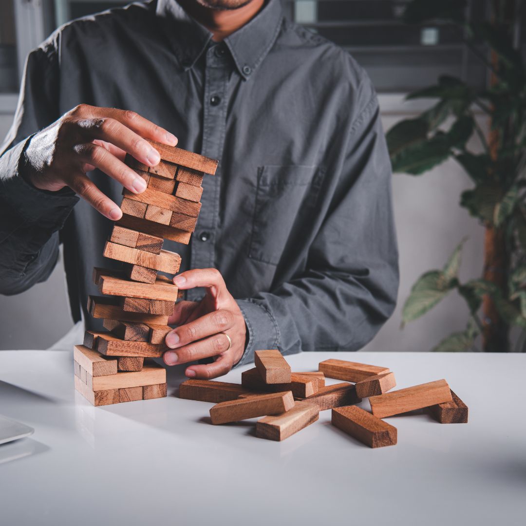 Man building a wooden block tower on white desk