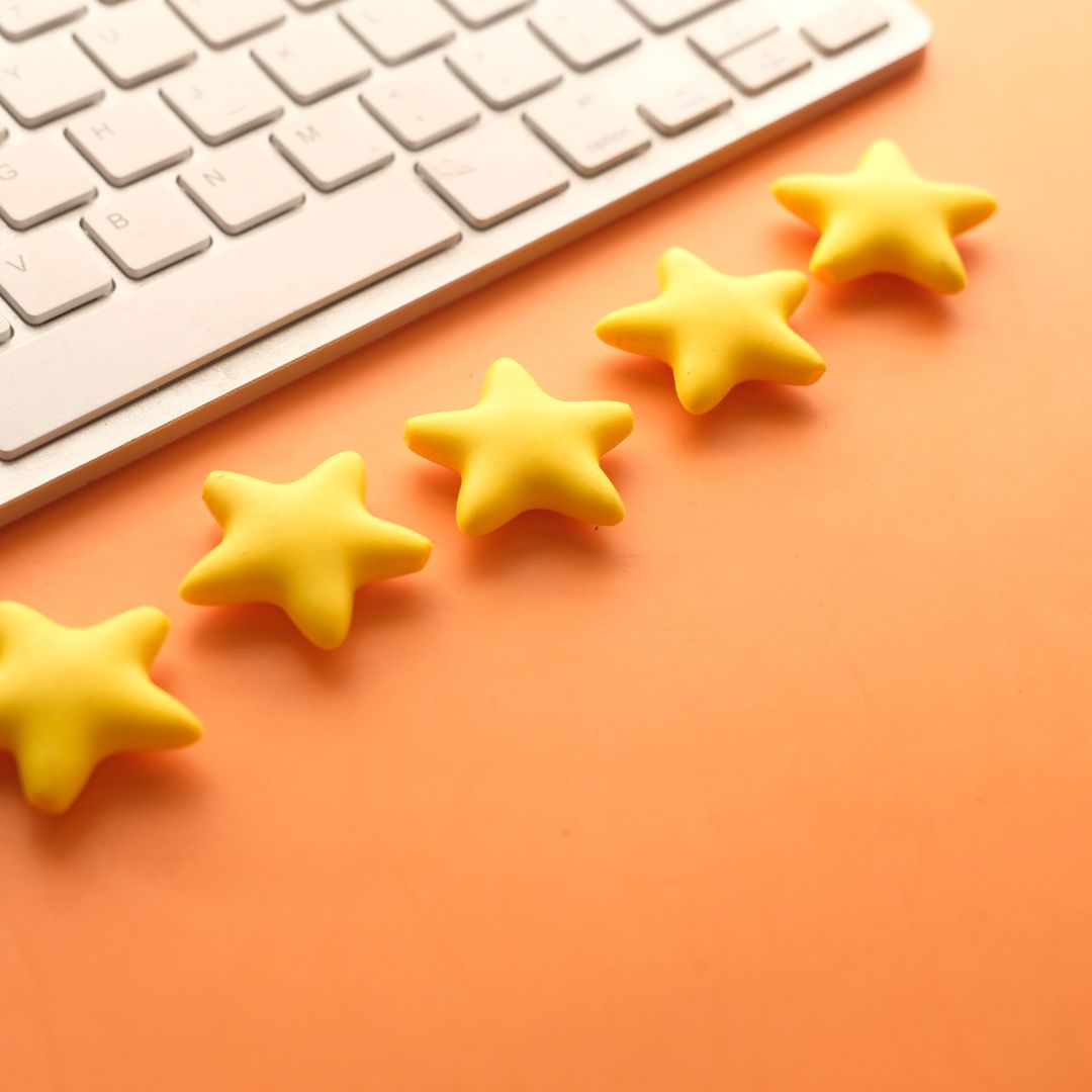 Five yellow stars next to a white keyboard on orange background