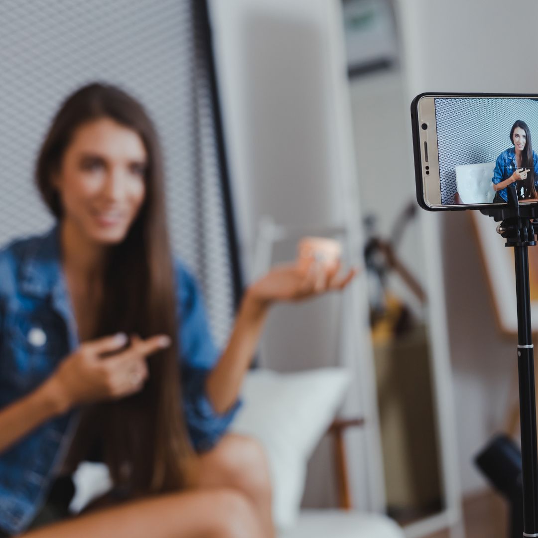 Woman pointing at product while filming with phone on tripod