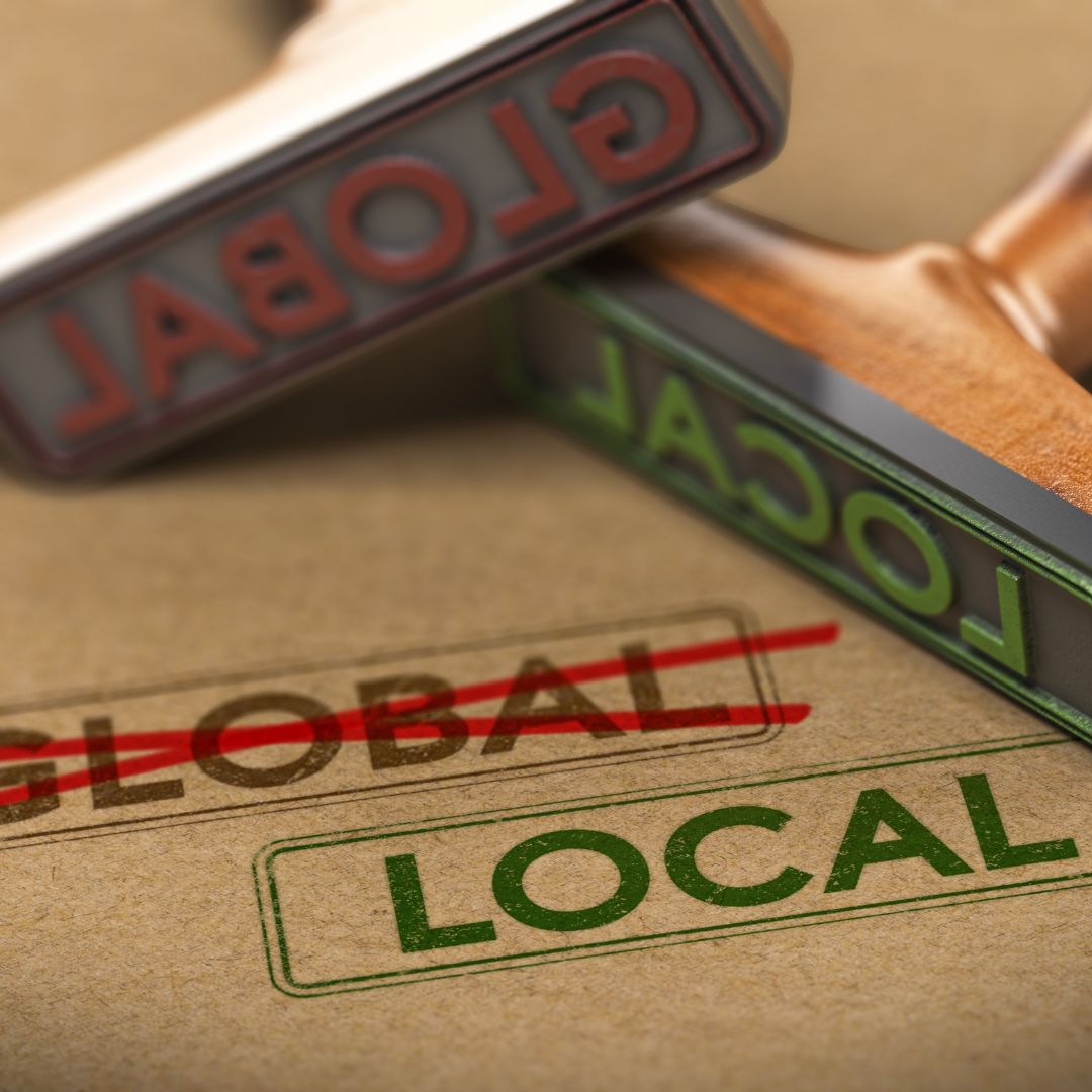 Stamp with LOCAL over crossed out GLOBAL on cardboard