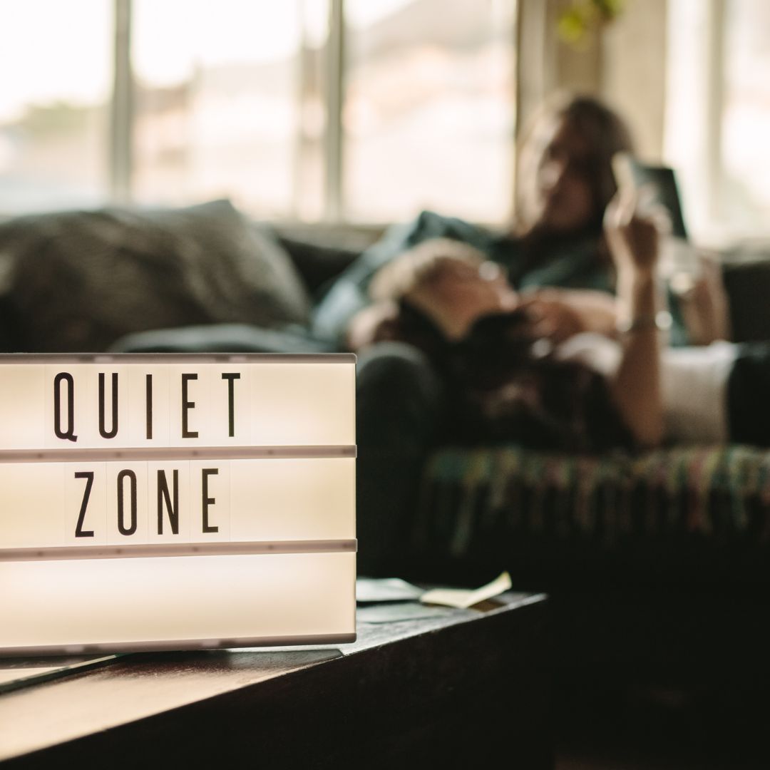 Lightbox saying QUIET ZONE with blurred background of people on sofa