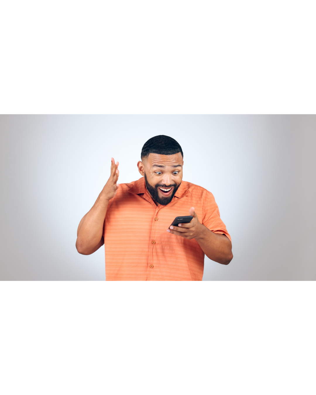 man in orange shirt holding phone excited about something