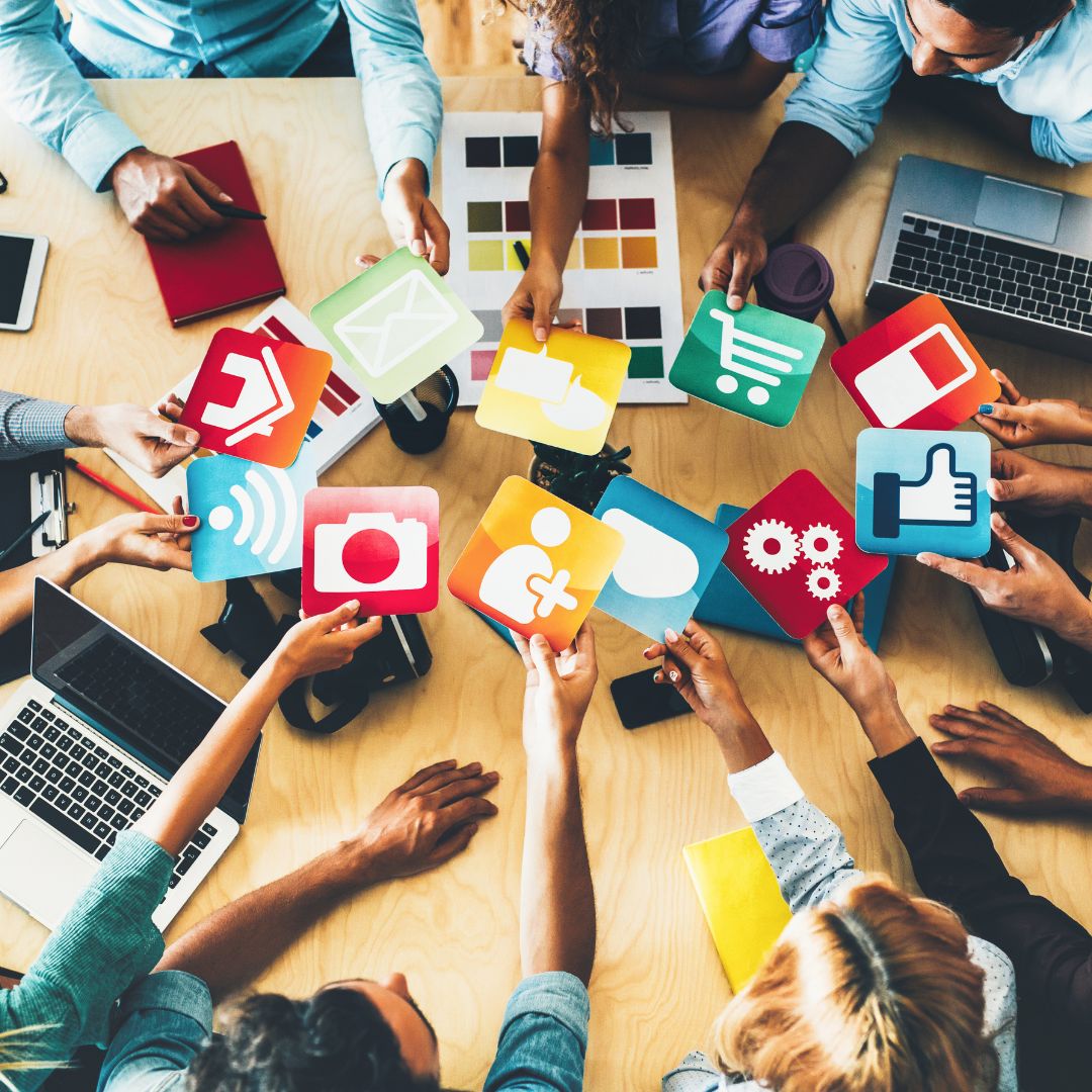 Group of people holding up social media icons during a creative planning session.