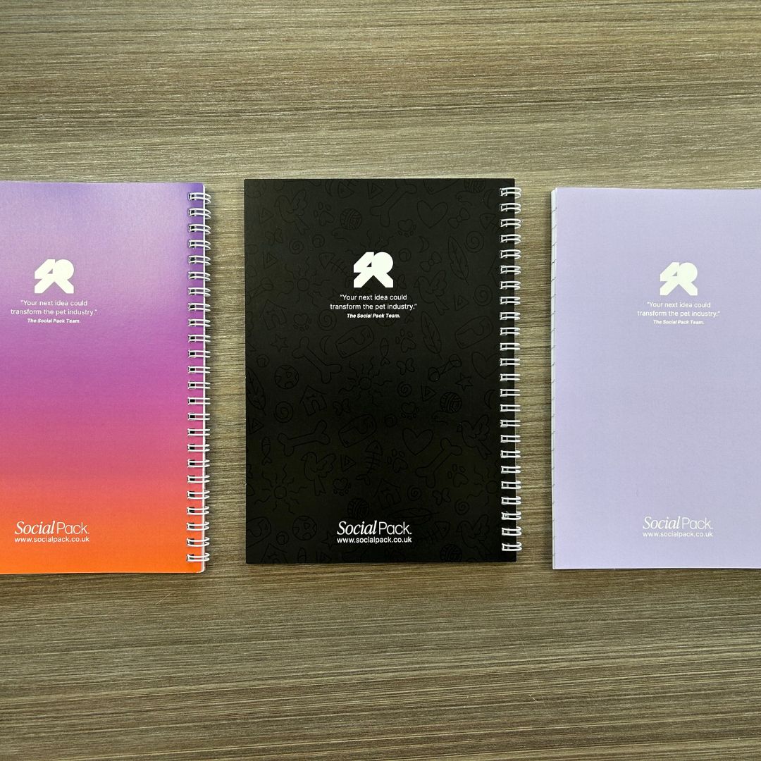 Three notebooks with different colored covers on a wooden surface