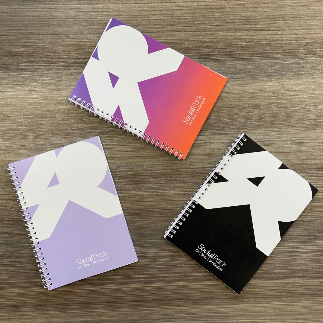 Three notebooks with different color covers on a wooden surface