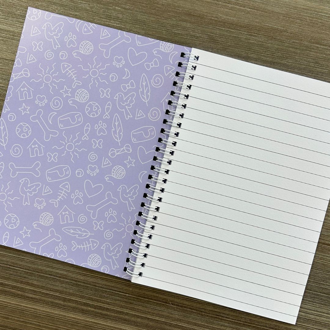 Notebook with purple patterned cover and white lined pages on a wooden surface