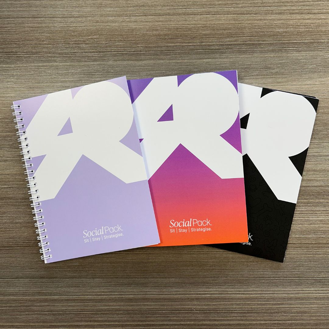 Three notebooks with abstract designs on a wooden surface