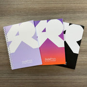 Three notebooks with abstract designs on a wooden surface